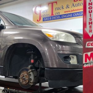 SUV on a two-post lift with the front wheels removed for suspension work
