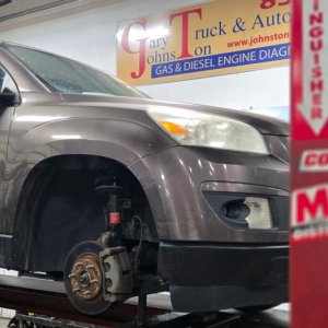 SUV raised on a lift beneath the Gary Johnston Truck and Auto sign
