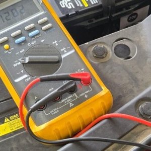 Technician testing an electrical circuit with a multimeter in the engine bay