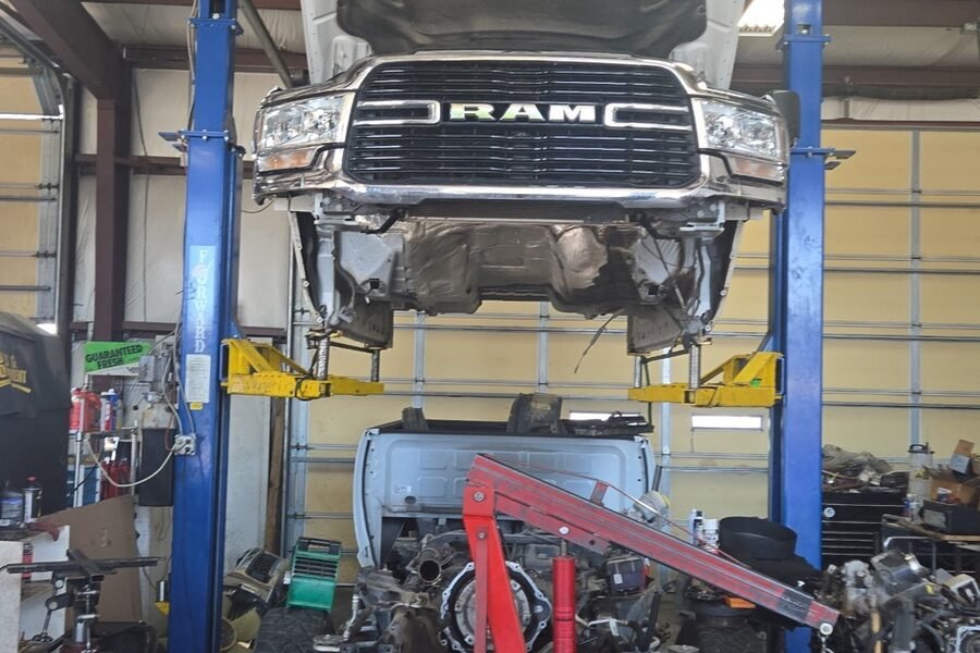 Heavy-duty truck on a lift with its engine and drivetrain lowered for transmission work