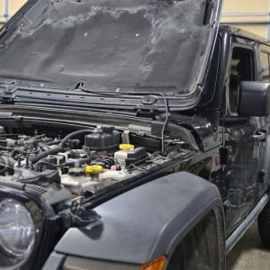Jeep Wrangler with the hood open undergoing engine service in the shop