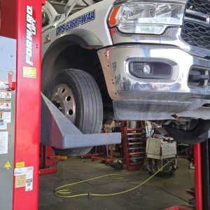 White commercial fleet truck raised on a Forward two-post lift with the front end disassembled for repair