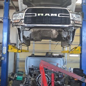 Heavy-duty truck on a lift with its engine and drivetrain lowered for transmission work