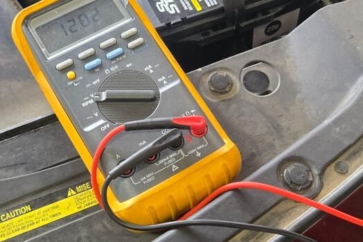 Technician testing an electrical circuit with a multimeter in the engine bay