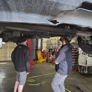 Two Gary Johnston technicians working underneath a vehicle raised on a lift