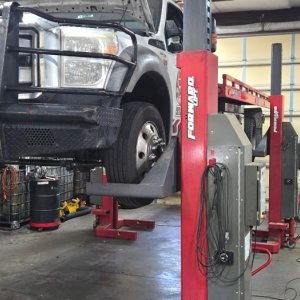 Pickup with a heavy-duty brush guard raised on a lift in the Gary Johnston service bay