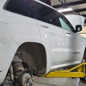 White Jeep Grand Cherokee in the service bay on a drive-on lift